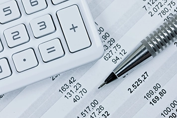 calculator and pen sitting on financial documents