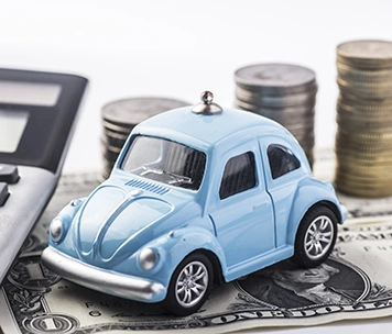 Toy Car next to calculator and stack of coins sitting on cash